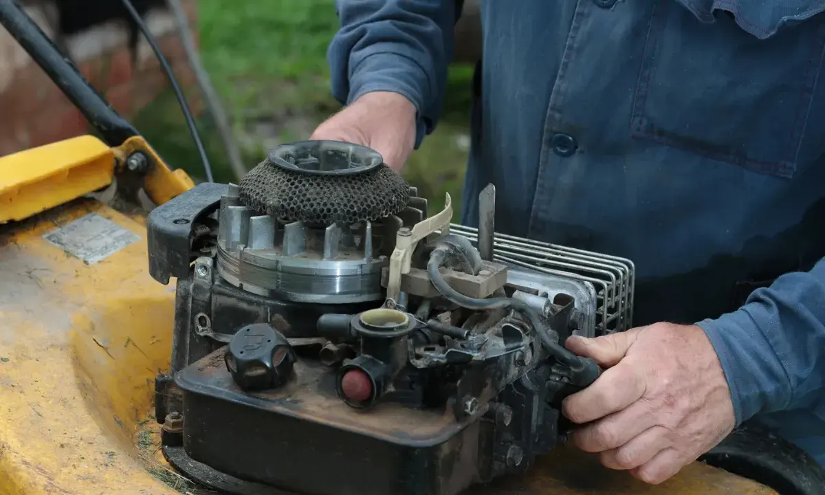 Ręce majsterkowicza przy silniku kosiarki Briggs & Stratton.