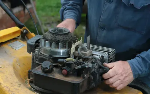 Ręce majsterkowicza przy silniku kosiarki Briggs & Stratton.